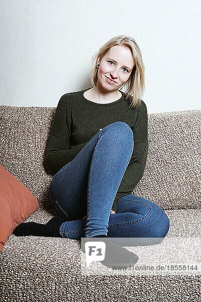young woman sitting on sofa relaxing at home