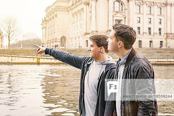 two male tourists exploring government district with Reichstag building and Spree river in Berlin Germany  tourism concept with sun flare filter