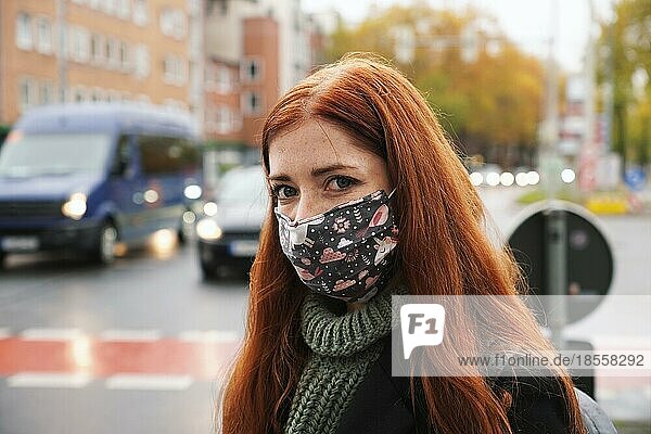 Junge Frau mit Gesichtsmaske im Freien als Fußgängerin im Stadtverkehr  neue normale Covid-19-Coronavirus-Pandemie und Luftverschmutzung Konzept  echte Menschen Lebensstil im Winter