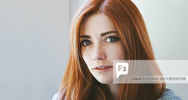 Junge Frau mit roten Haaren und Sommersprossen - rothaariges Mädchen mit sommersprossigem oder sommersprossigem Gesicht - Innenporträt mit natürlichem Licht