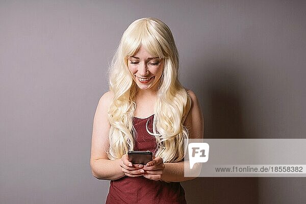 happy smiling young woman looking down at text message on her smartphone - mobile communication and social media concept