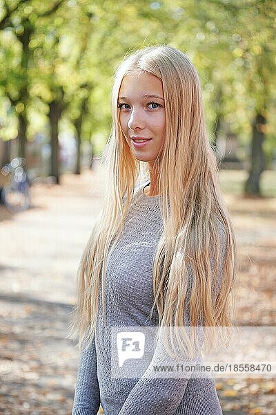 Porträt eines Teenagers mit langen blonden Haaren  der einen sonnigen Tag im Freien genießt