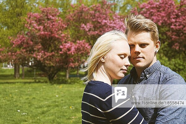 young couple in love hugging in nature during cherry blossom in park