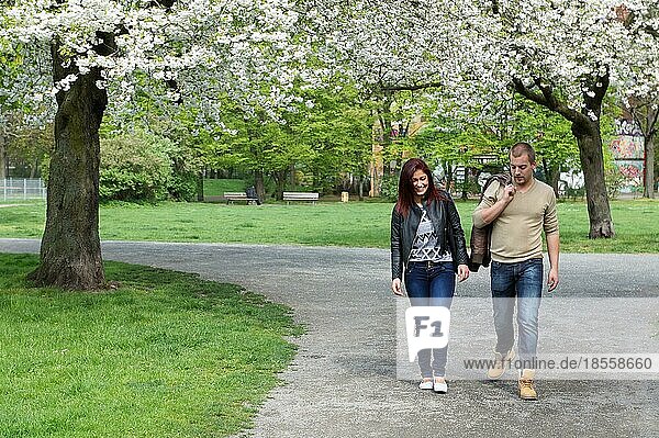 young couple strolling through a park in spring