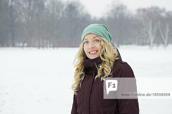 blond woman wearing warm winter fashion walking on snowy field