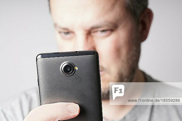 middle aged man looking at mobile smartphone or taking selfie. shallow depth of field