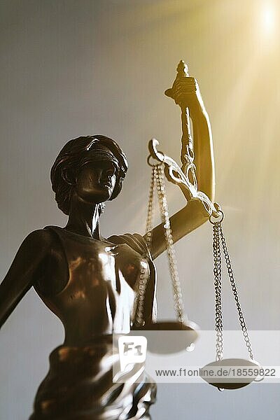 Lady Justice oder Justitia mit verbundenen Augen  die eine Waage hält - Recht und Rechtssymbol - mit Sonnenstrahlen Lichtleck