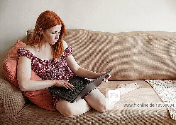 young woman using laptop computer at home relaxing on sofa