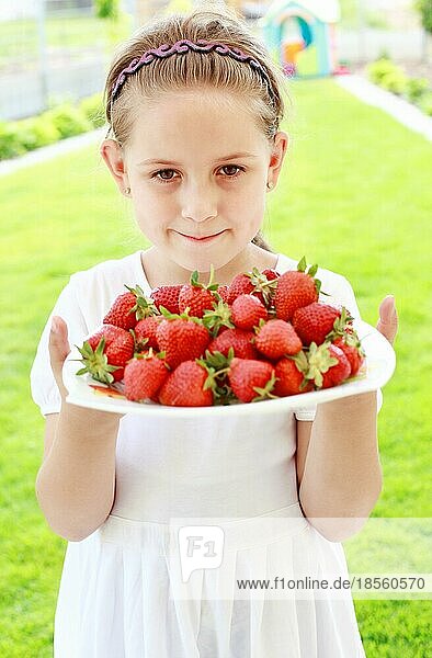 Niedliches Mädchen hält Teller mit frischen Erdbeeren
