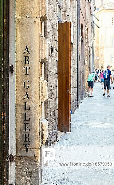 Toskana  Italien. Ein Kunstgalerie Schild in einer Straße voller Touristen