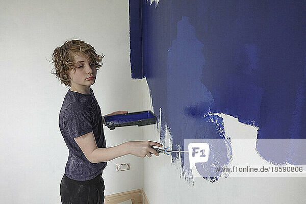 Boy painting wall with blue paint