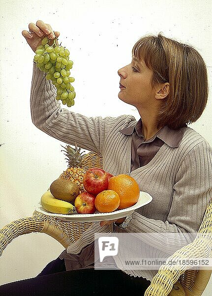 Junge Frau mit Weintrauben und Obstteller