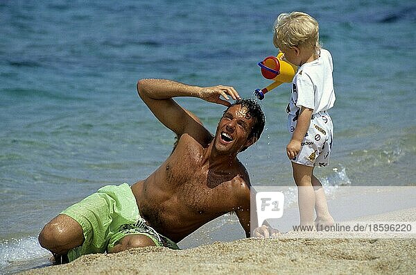 Mann spielt mit Kind am Strand