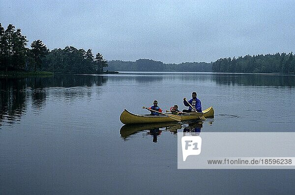 Father and 2 children paddling a canoe