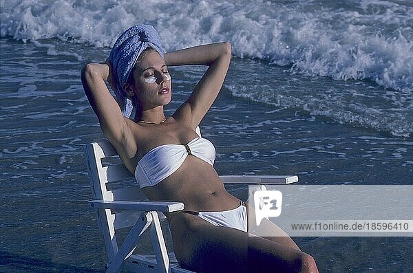 Kosmetik Frau nimmt Sonnenbad mit Maske am Strand