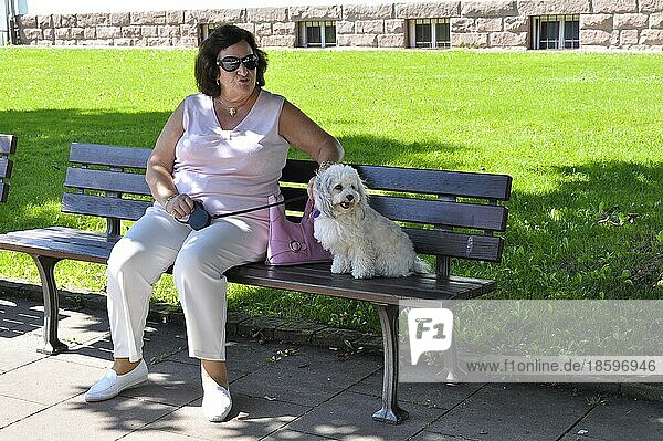 Elderly woman with dog on park bench