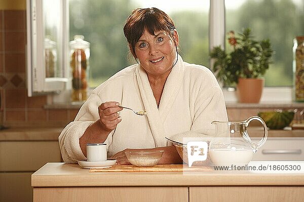 Frau beim Frühstück  Frühstück  frühstücken  Kanne Milch  Schüsseln  Müsli  Tasse Kaffee  frühstückt  Löffel
