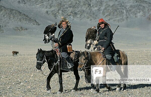 Kazak men Golden Eagles (Aquila chrysaetos) capped with leather hoods  on horses  Golden Eagle Festival  province Bayan Olgiy  Mongolia  Asia