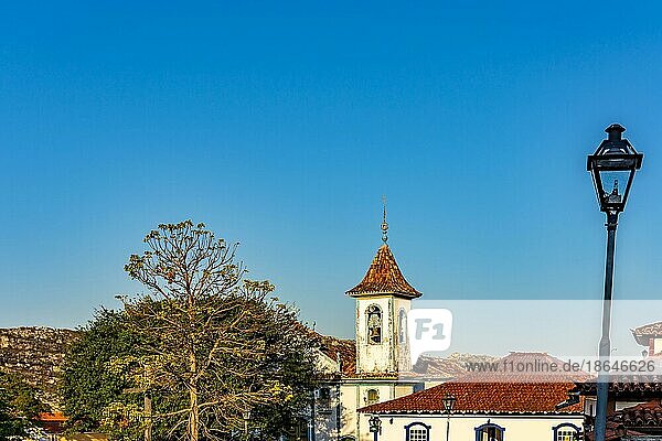Barocker Kirchturm mit Glocke  der durch die Bäume und Dächer der historischen Stadt Diamantina in Minas Gerais  Brasilien  ragt  Südamerika