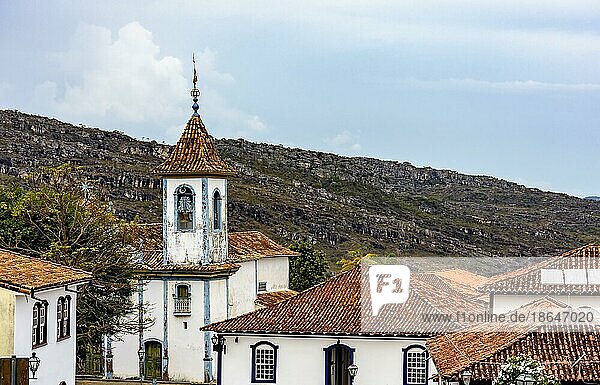 Historischer barocker Glockenturm einer Kirche  der durch die Bäume  Dächer und Berge der historischen Stadt Diamantina in Minas Gerais  Brasilien  ragt  Südamerika
