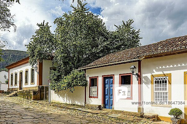 Blick auf alte bunte Kolonialhäuser in einer gepflasterten Straße in der historischen Stadt Tiradentes in Minas Gerais  Brasilien  Südamerika