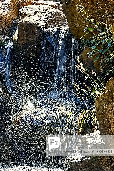 Kleiner Wasserfall mit fließendem und glänzendem Wasser zwischen Felsen und Vegetation  Brasilien  Südamerika