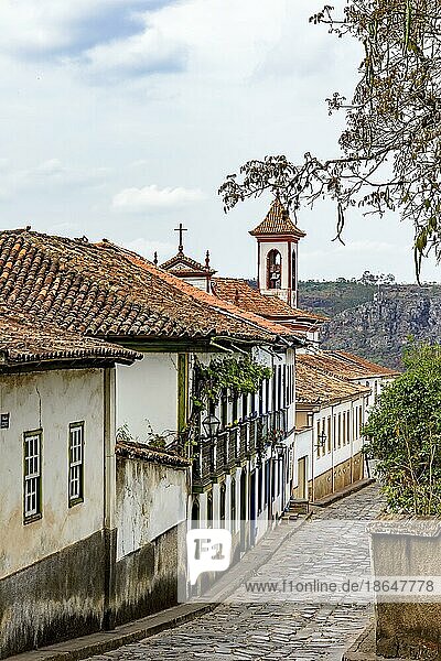 Gepflasterte Straße in der Stadt Diamantina mit ihren Häusern im Kolonialstil und bunten Balkonen mit dem Glockenturm der Kirche im Hintergrund  Brasilien  Südamerika