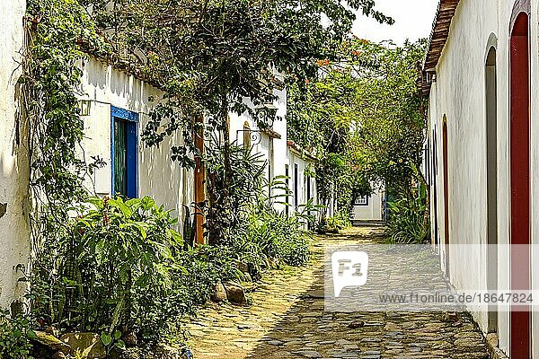 Schöne Straße in der historischen Stadt Paraty mit Kopfsteinpflaster und alten Häusern im Kolonialstil  deren Fassade mit Pflanzen und Blumen geschmückt ist  Brasilien  Südamerika
