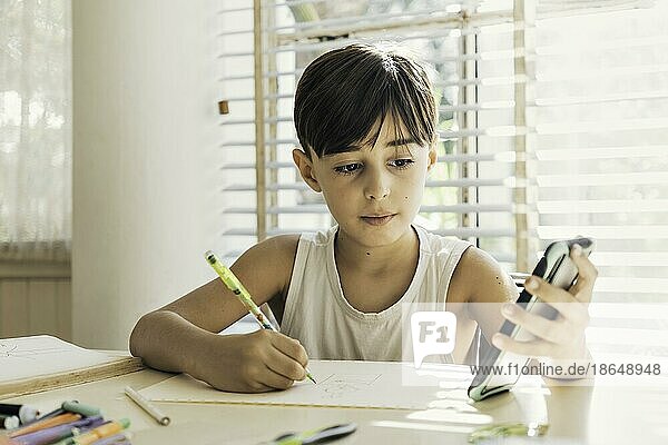 Ein Kind sitzt zu Hause mit einem Stift in der Hand und zeichnet und malt. Prozess des Lernens und der kreativen Entwicklung von Kindern