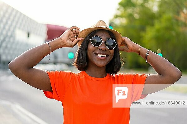 Sommerliche Stimmung: Junge schwarze Touristin in grünem TShirt und Sonnenbrille vor brauner Wand  Lifestylefotos