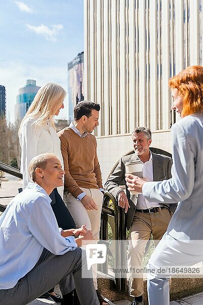 Cheerful group of coworkers outdoors in a corporate office area resting