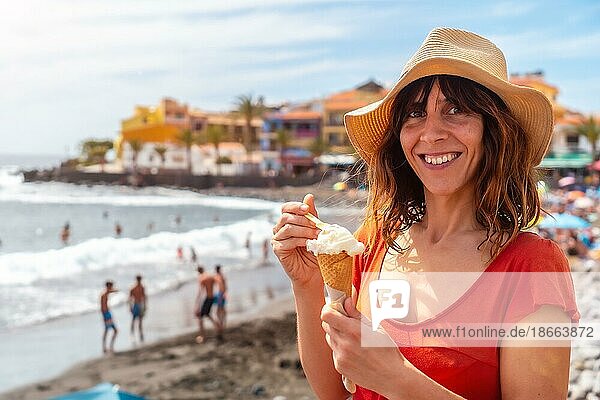 Touristin mit Hut isst ein Eis am Strand im Sommer am Strand von Valle Gran Rey auf La Gomera  Kanarische Inseln