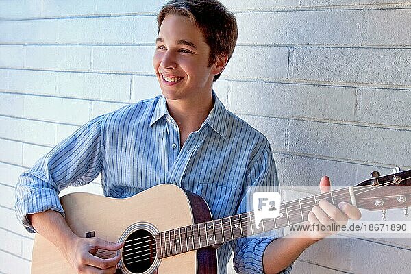 Lächelnder junger Mann spielt Gitarre