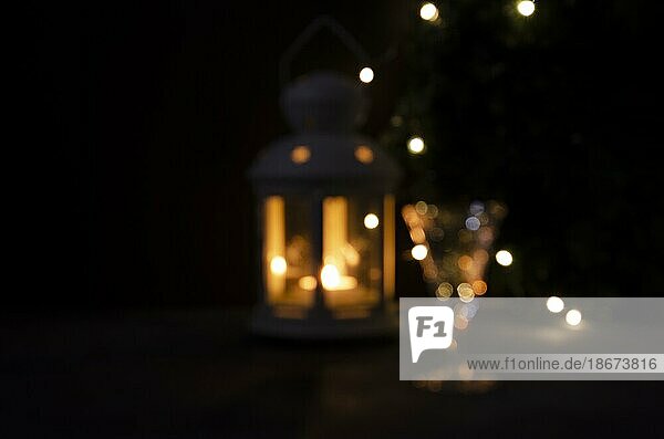 Glänzend verschwommener Hintergrund für Design. Glas mit Weißwein mit Girlande Lichter und Kerze Laterne verschwommen. Nacht Bild. Schöne Lichter
