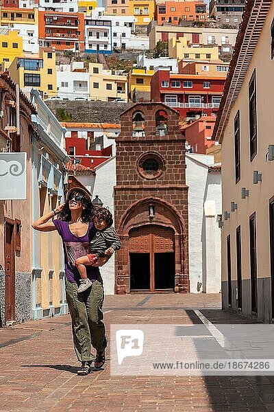 Vacation concept  mother with her son in her arms in the city of San Sebastian de la Gomera next to the Iglesia De La Asuncion  Canary Islands