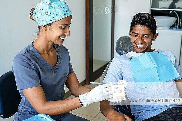 Zahnarzt zeigt einem Patienten ein Modell eines Backenzahns  um die Behandlung zu erklären