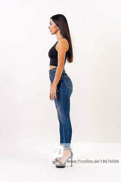 Brunette woman in casting photos on a white background  in jeans and a black t-shirt in profile