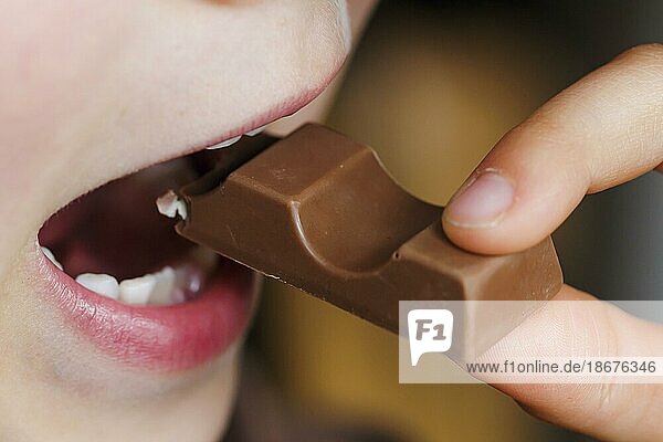 Symbolfoto zum Thema Schokolade essen. Ein Junge beißt von einem Schokoriegel ab. Berlin  19.05.2023  Berlin  Deutschland  Europa