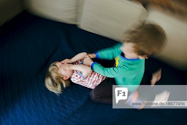 Symbolfoto zum Thema Streit unter Geschwistern. Ein zweijähriges Mädchen und ein fünfjähriger Junge prügeln sich zu Hause auf einer Couch. Berlin  19.05.2023  Berlin  Deutschland  Europa