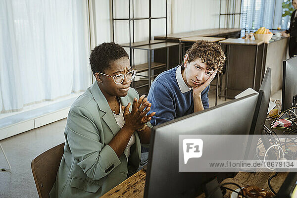 Angespannte männliche und weibliche Programmierer  die in einem kreativen Büro auf einen Computerbildschirm schauen
