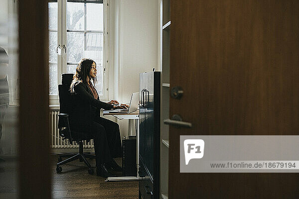 Unternehmerin sitzt auf einem Stuhl und arbeitet im Büro