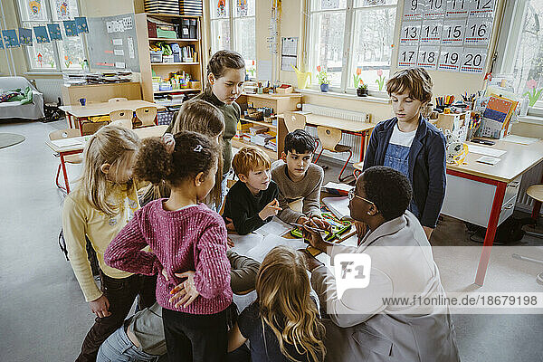 Lehrerin  die Jungen und Mädchen im Klassenzimmer der Grundschule betreut