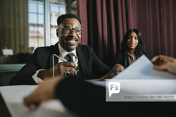 Happy mature businessman wearing eyeglasses in board room at office