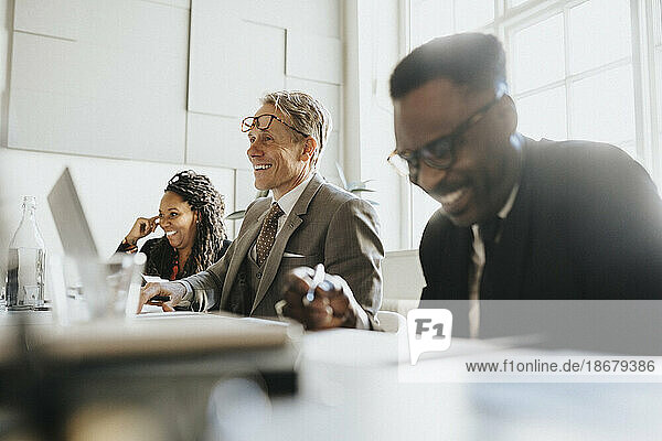 Lächelnder reifer Unternehmer mit männlichen und weiblichen Kollegen bei einem Treffen im Büro