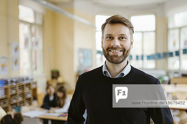 Porträt eines lächelnden männlichen Lehrers mit Bartstoppeln im Klassenzimmer