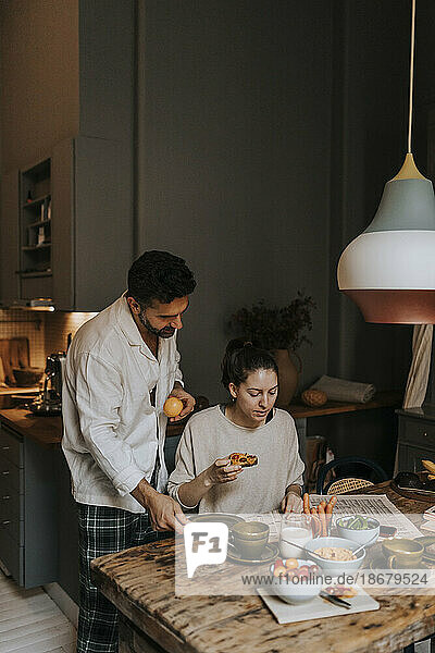 Ehepaar liest Zeitung beim Frühstück zu Hause