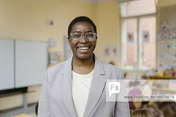Porträt einer glücklichen Lehrerin mit Blazer im Klassenzimmer