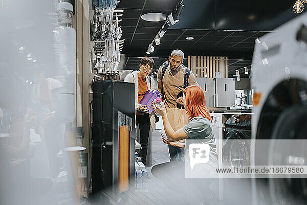Verkäuferin  die männlichen und weiblichen Kunden beim Kauf eines Geräts in einem Elektronikgeschäft hilft