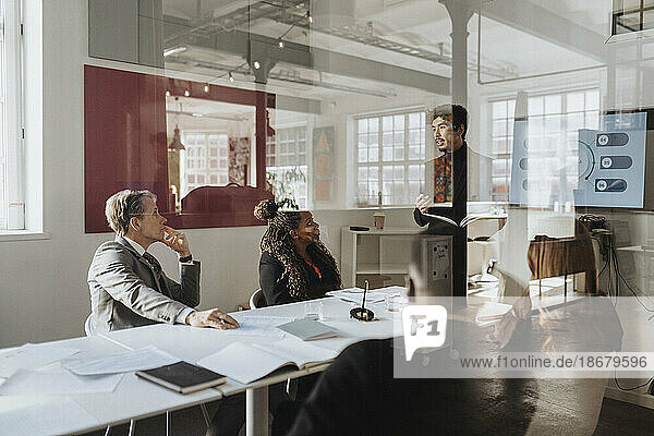 Geschäftskollegen  die eine Sitzung im Sitzungssaal eines Büros abhalten  gesehen durch Glas