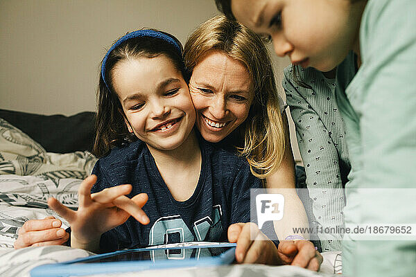Glückliche Frau mit Söhnen  die zu Hause ein digitales Tablet benutzen